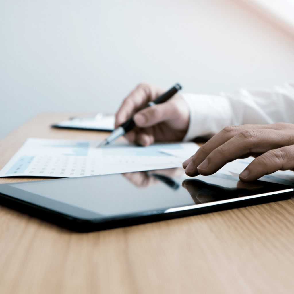 a man holding a tab and pen with paper on his desk